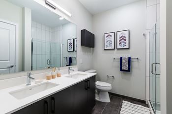 A bathroom with two sinks and a shower and a toilet